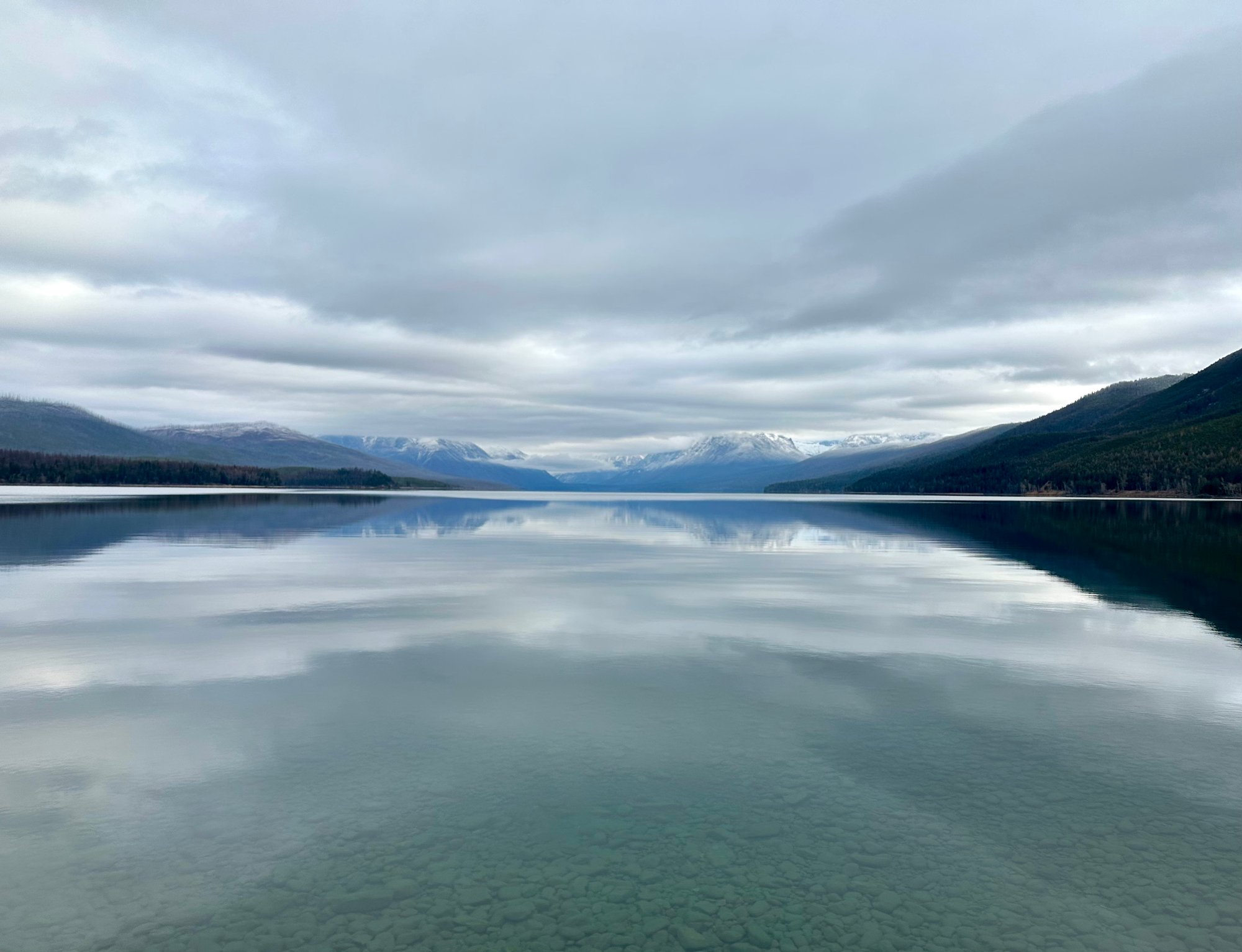 A lake with mountains in the distance on a blue-gray day A lake with mountains in the distance on a blue-gray day